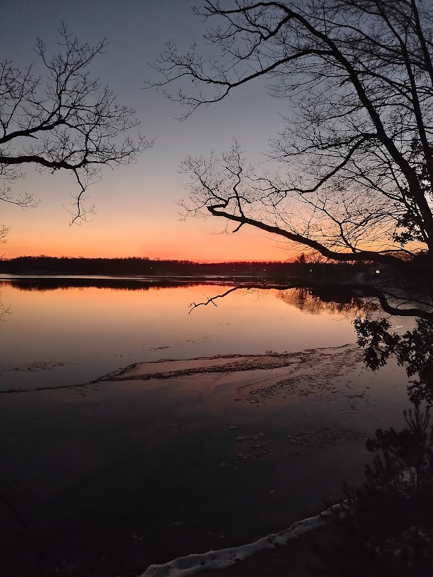 Peach sunset colors reflecting on calm lake.